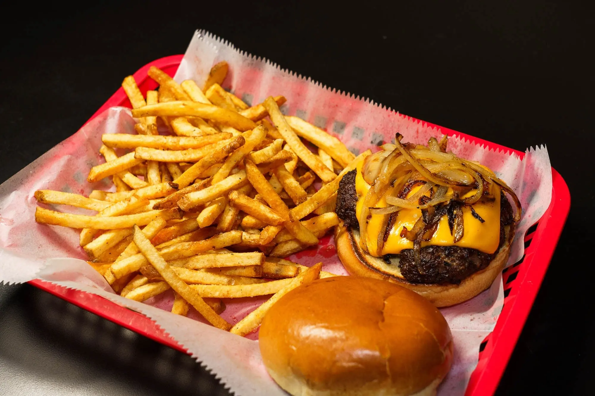 The Butter Burger with melted cheese and grilled onions in a red basket with sea-salt fries and a toasted bun
