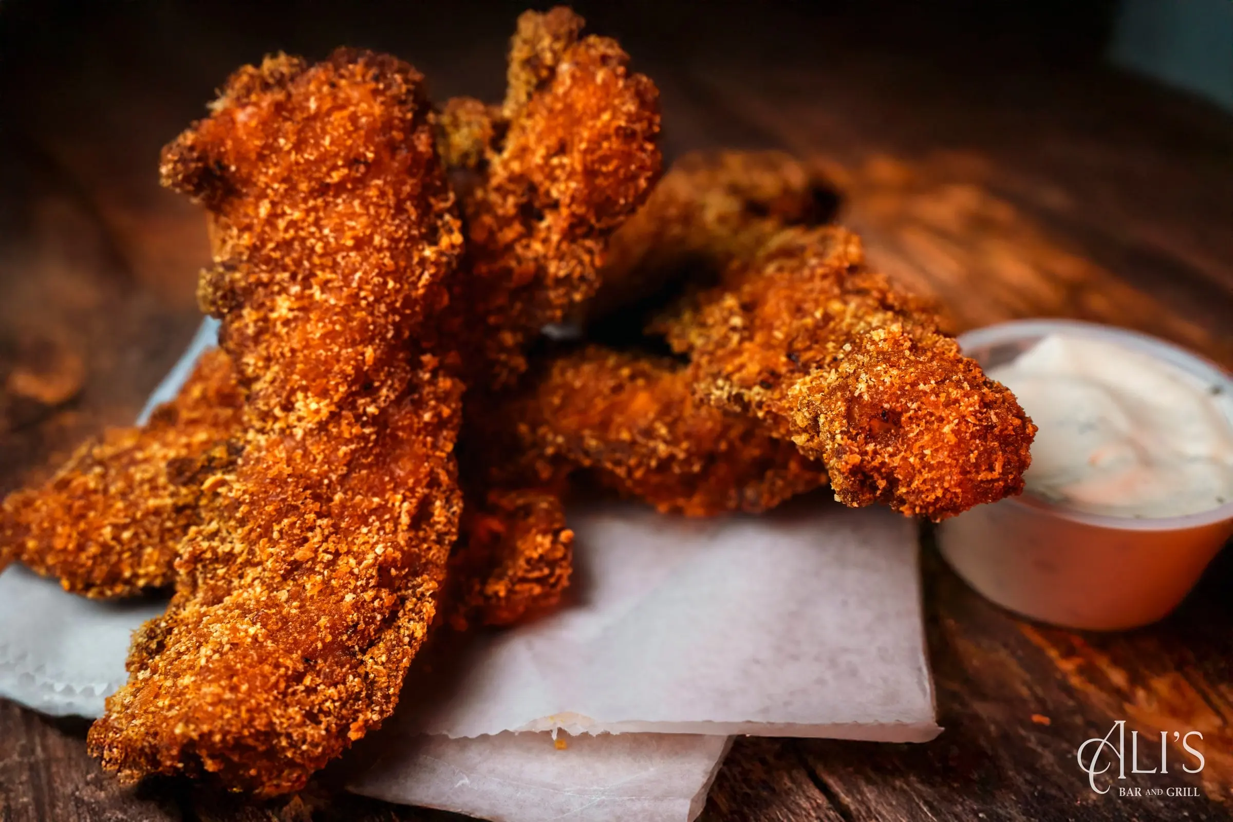 Chicken Crunch: cereal-crusted fried chicken strips with a cup of creamy dipping sauce on a wooden board